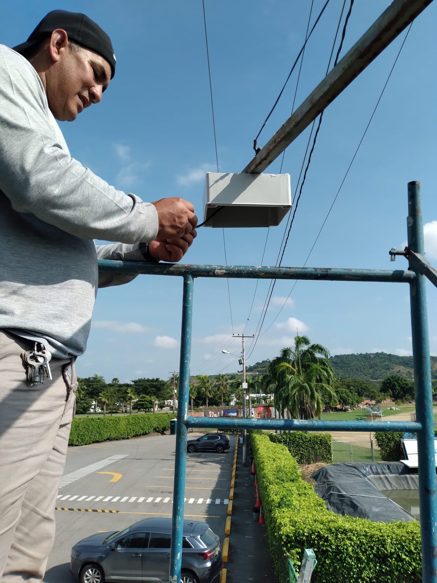 Técnico de INVOCE instalando gabinete de intemperie sobre estructura, en el acceso vehicular de una urbanización.