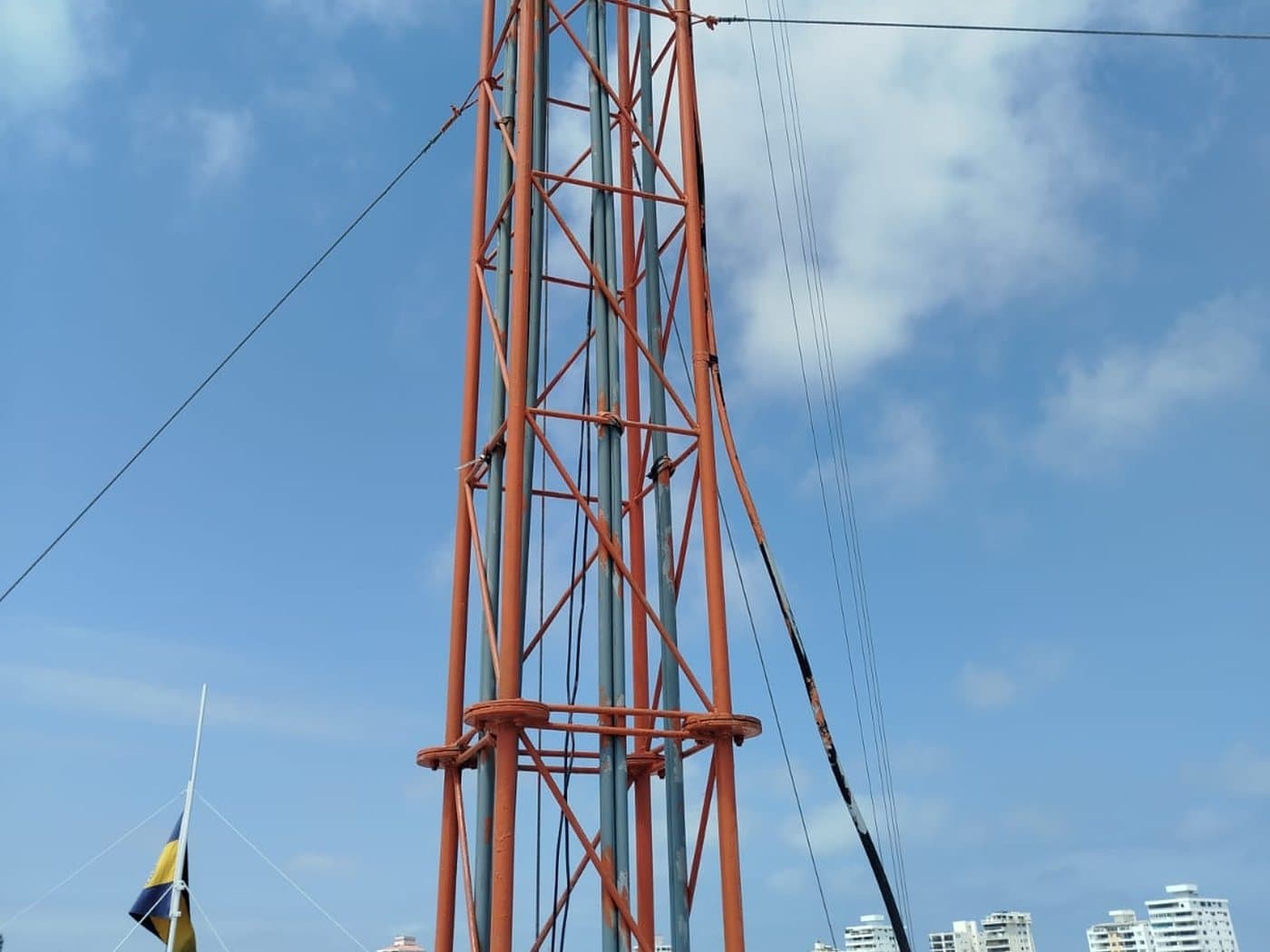 Detalle de la estructura de una torre arriostrada con sus riendas y bajantes, sobre una marina.